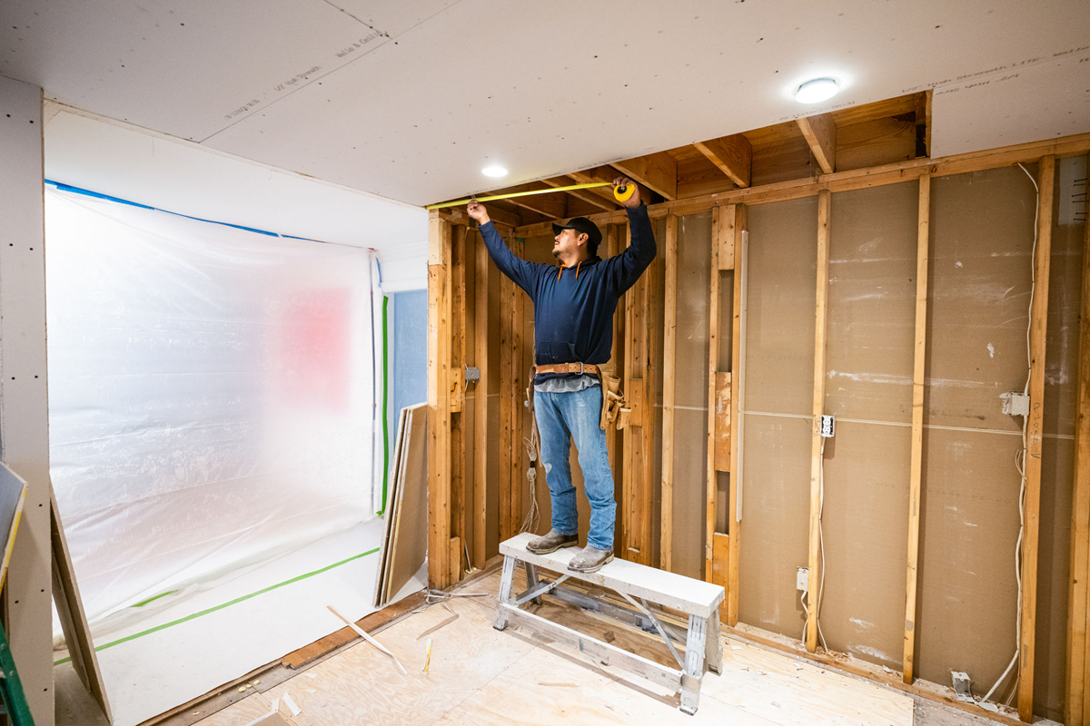 Worker installing ceiling lights in room
