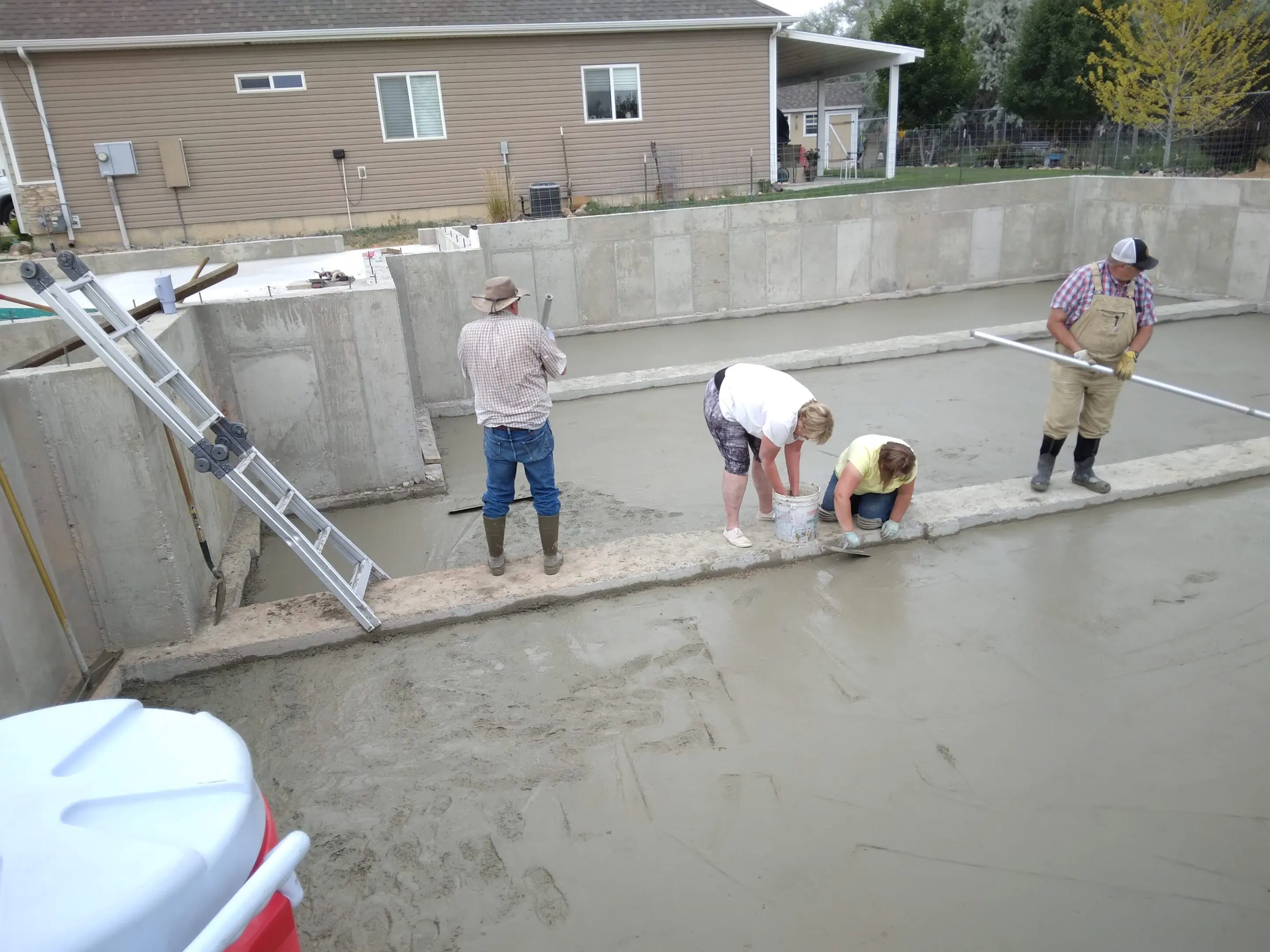 Workers pouring and smoothing concrete on a construction site.