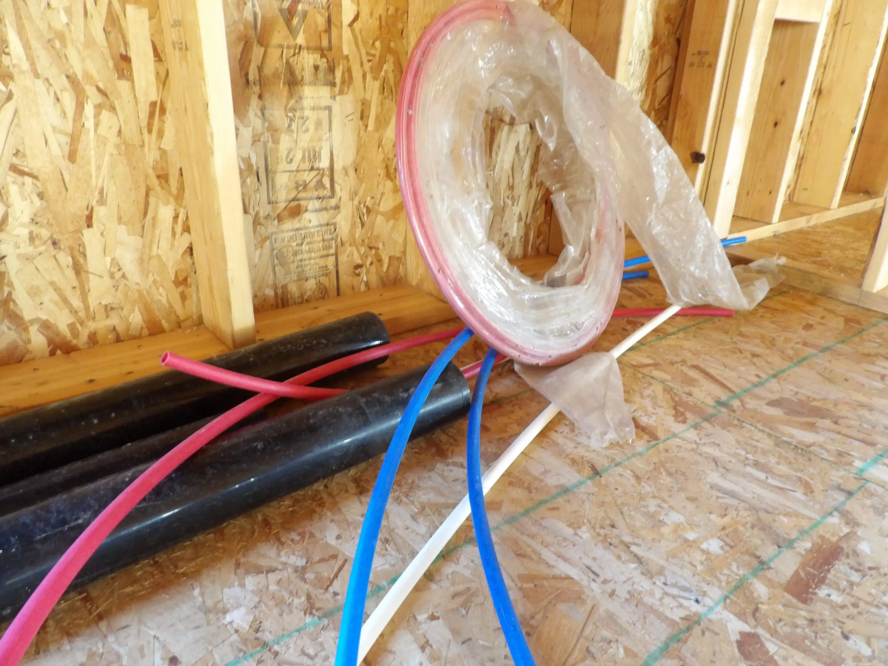 Pipes with plastic-wrapped circular component inside wooden frame.