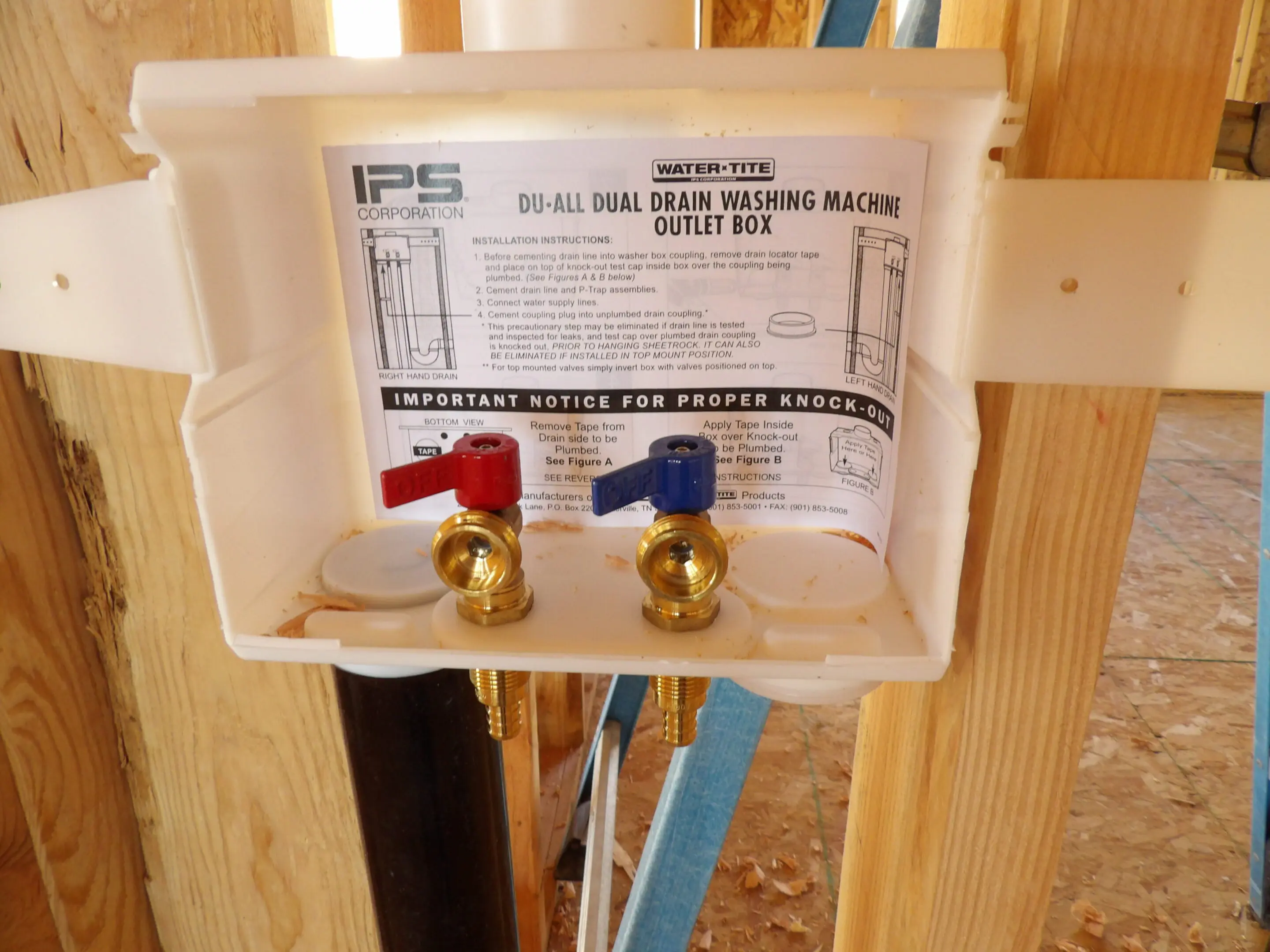 Dual valve water supply box installed in wooden framing.