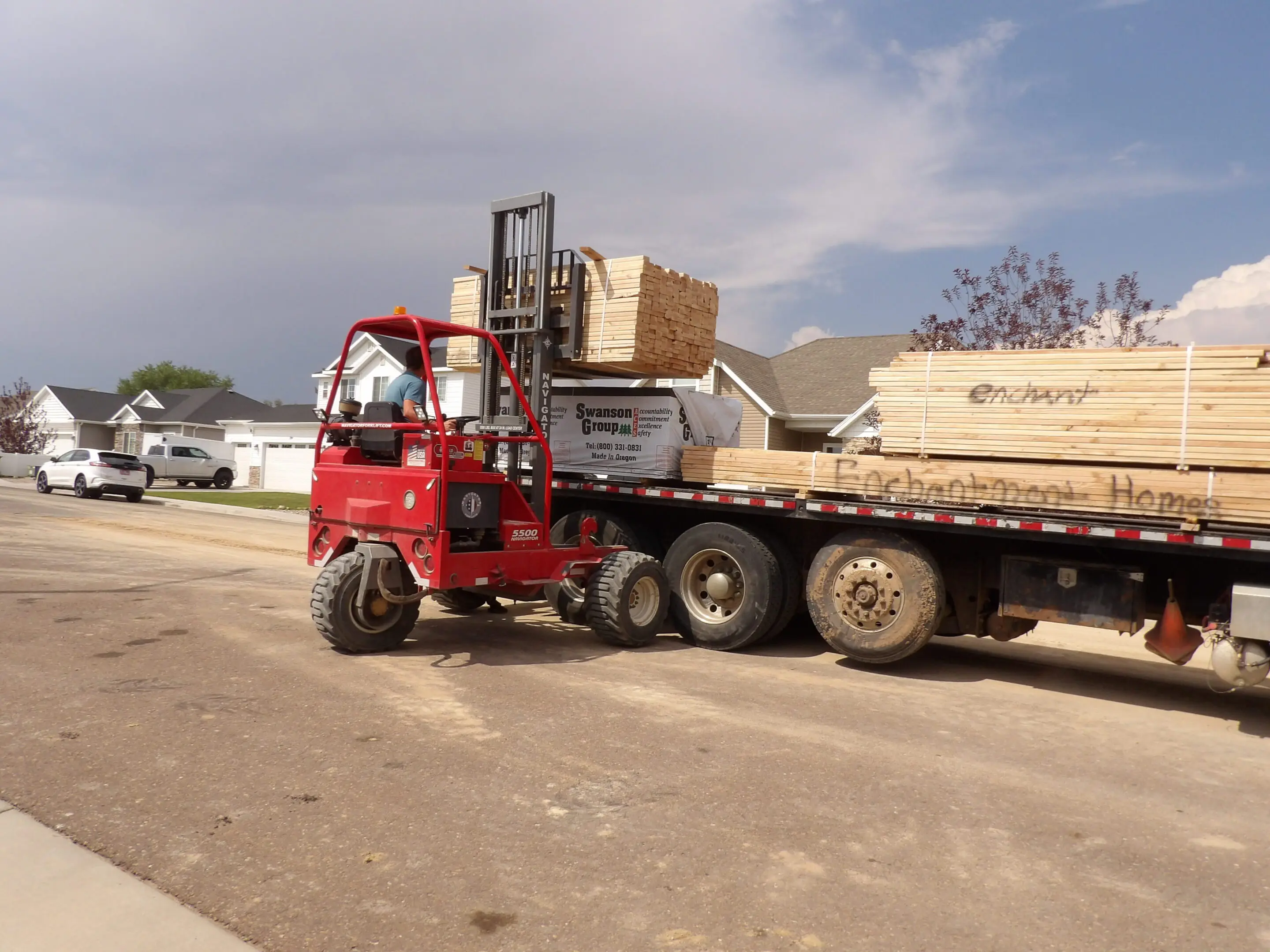 A red flatbed truck carrying construction materials on a cloudy day.