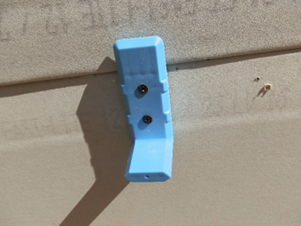 A blue handle is attached to the side of a wall.